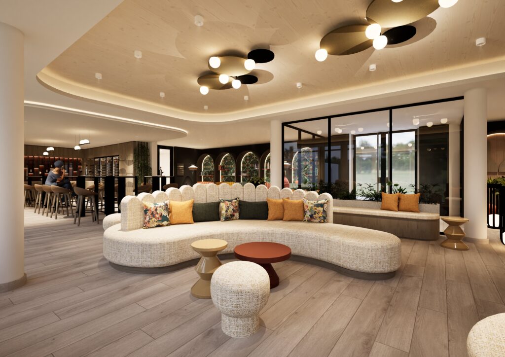Der moderne Lounge-Bereich besteht aus einem geschwungenen beigen Sofa mit bunten Kissen, kleinen runden Tischen und Hockern. Große Fenster und dekorative Deckenleuchten erhellen den Raum, der sich perfekt zum Entspannen nach einem weinreise gutschein Erlebnis an der Bar eignet.